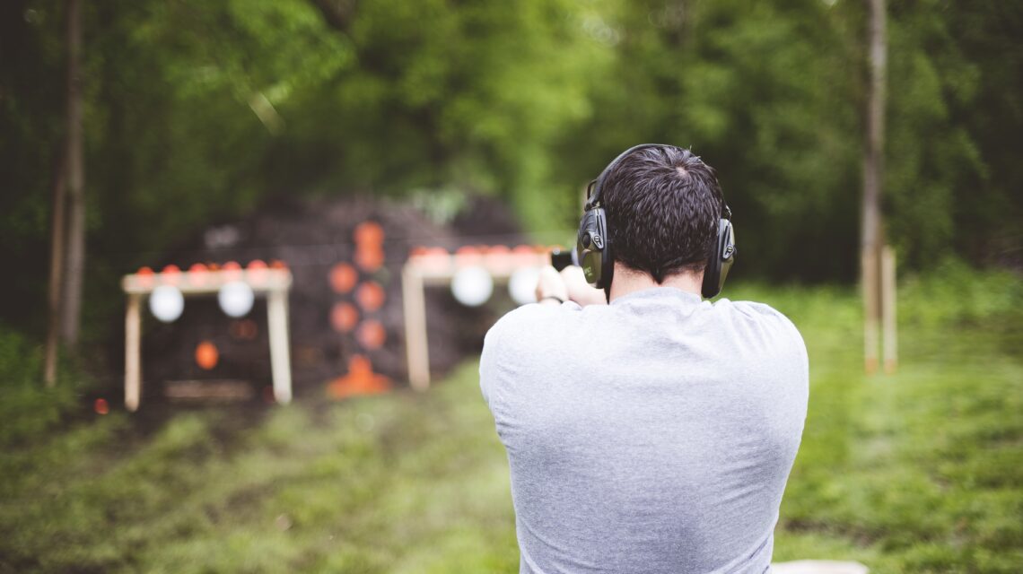 Shallow focus shot from behind of a male shooting a gun at a gun range