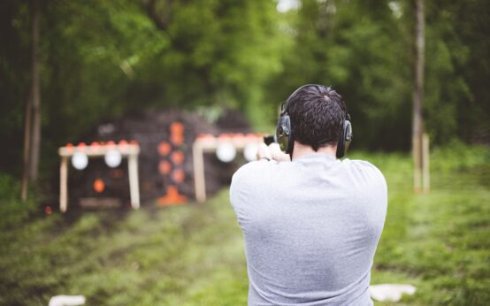 Shallow focus shot from behind of a male shooting a gun at a gun range